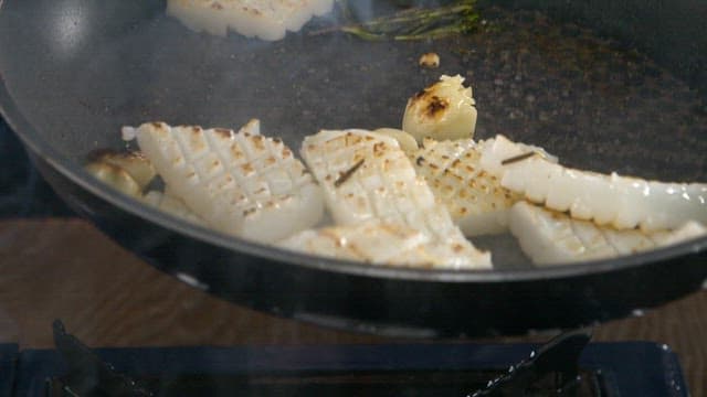 Squid being grilled until golden brown in a pan
