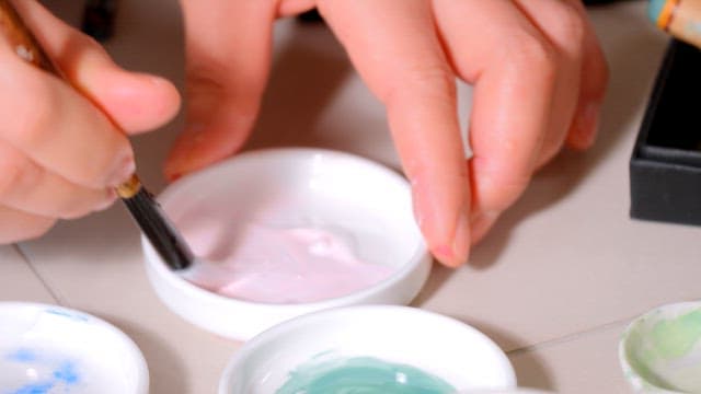 Painter's Hands Mixing Paint with a Brush