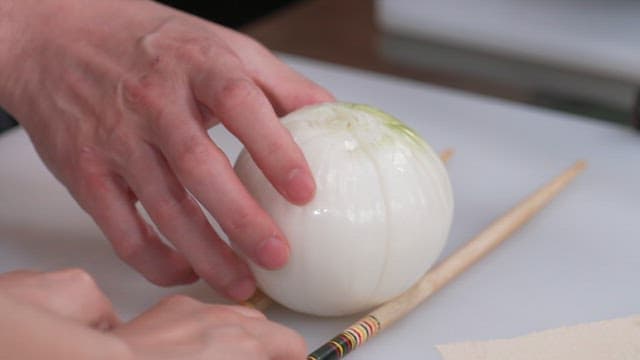 Cutting Fresh Onion with a Knife on a Cutting Board