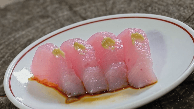 Slices of pink tuna sushi on a white plate