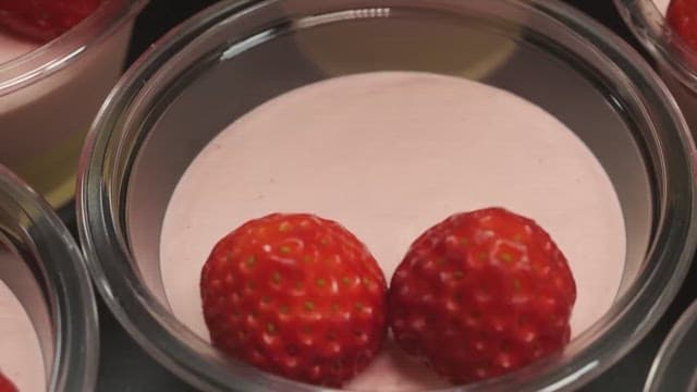 Careful placement of strawberries on a pink mousse dessert.