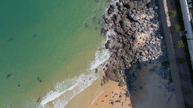 Peaceful rocky beach with clear green waters and few people