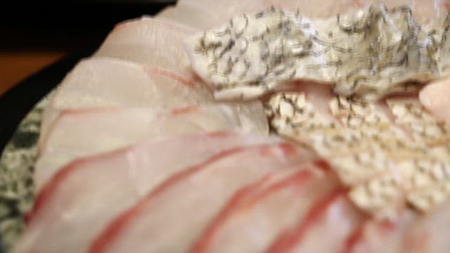 Close-up view of fresh sashimi being held by chopsticks