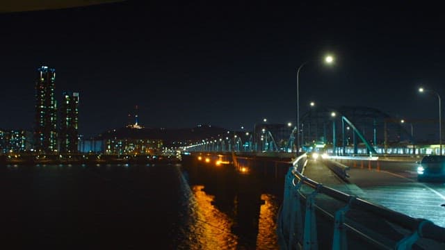 Night view of the city with lit buildings and a bridge over the river