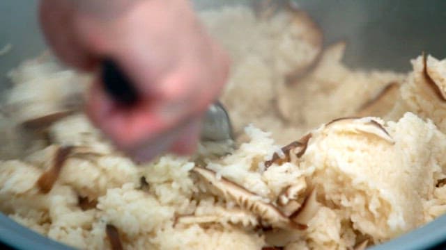 Wice with steaming shiitake mushrooms being stirred with a spatula