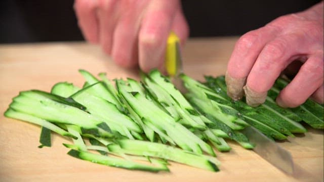 Slicing fresh cucumbers on a wooden cutting board