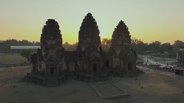 Overview of a Bustling Street with Ancient Temple Ruins and Sunset