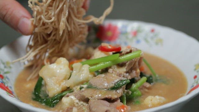 Delicious Thai dish made with vegetables and meat, topped with fried noodles, Lad na