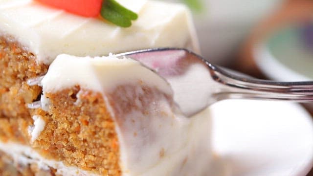 Fork holding carrot cake with cream cheese frosting