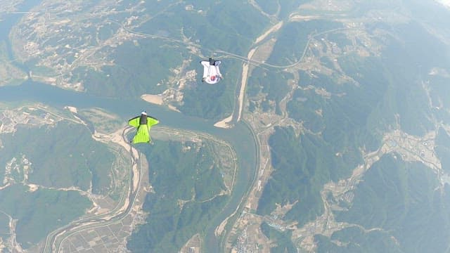 Wing-suited Adventurers Soaring over Scenic Land