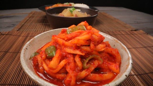 Table with julienne Korean radish salad, rice bowls, and soup