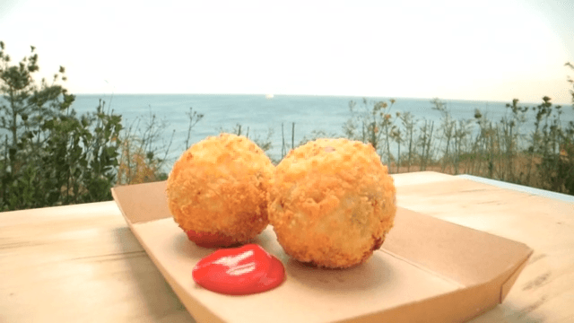 Crispy potato croquettes and ketchup plated on a table by the sea