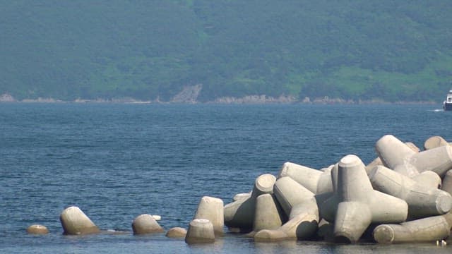 Ferry coming into a beach with a breakwater