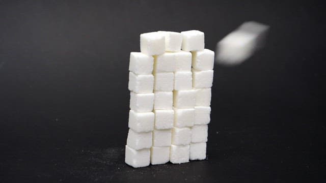 Stacked white sugar cubes on a black surface