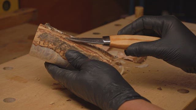 Hands carving wood with a knife