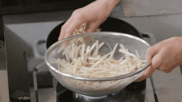 Pouring oil into a hot pan to fry vegetables