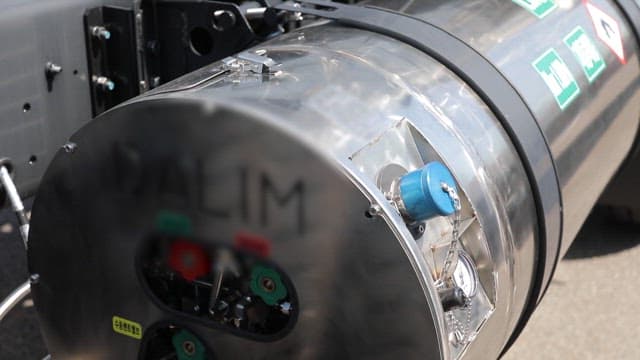 Industrial LNG tank with a blue valve and warning labels