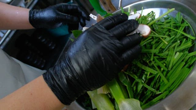Fresh greens and mushrooms in a metal bowl on a kitchen countertop