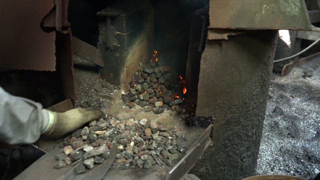 Worker tending to a furnace with coal