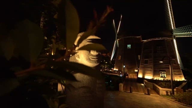 Dolhareubang and illuminated windmill at night