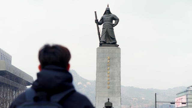 Man looking at the statue of admiral Yi Sun-sin at Gwanghwamun square