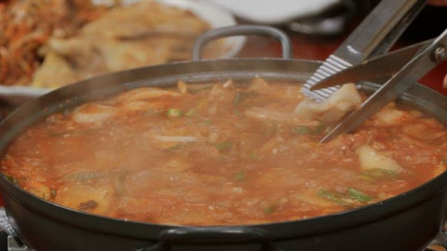 Cutting meat in kimchi stew with scissors in a pot