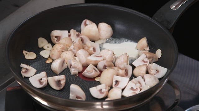 Cooking mushrooms with butter and garlic in a pan