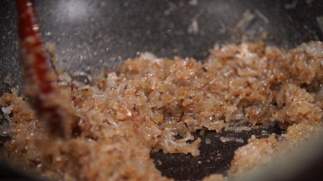 Stir-frying minced meat and noodles in a pan with a wooden spatula