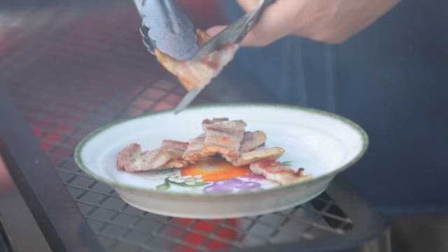 Grilled pork belly being placed on a plate