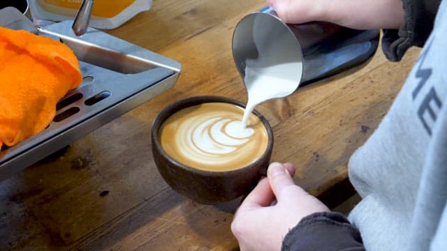 Barista Serving Coffee with Latte Art Using Milk Foam