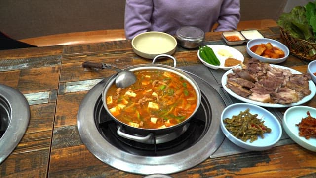 Delicious Korean meal with various side dishes, boiled meat and stew