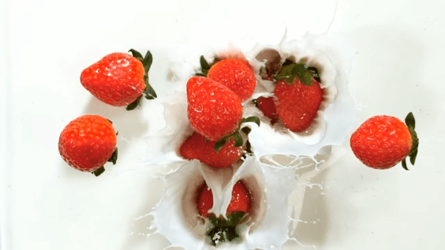 Strawberries falling into milk