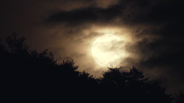 Full Moon Shining Through Clouds at Night