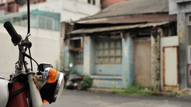 An old motorbike parked outside a weathered building