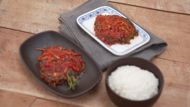 Wooden table neatly decorated with white rice and perilla leaf kimchi