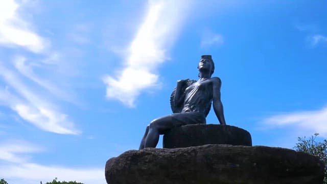 Statue of a figure against a blue sky