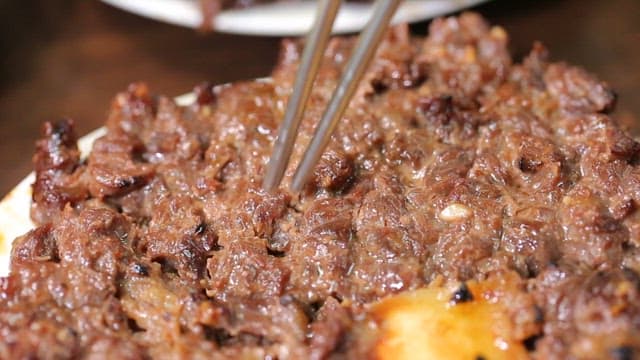 Grilled beef being picked up with chopsticks