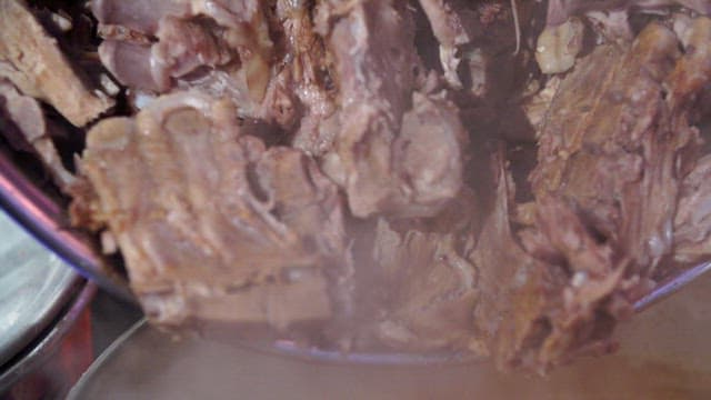 Pork backbones being added to a seasoning broth