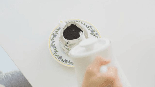 Making drip coffee by pouring water with coffee pot at a white table