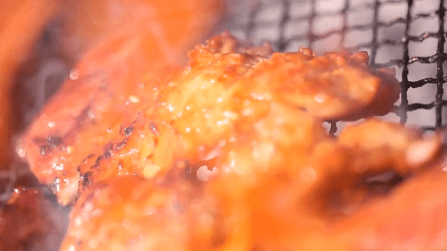 Grilling marinated pork ribs on a grill over burning charcoal