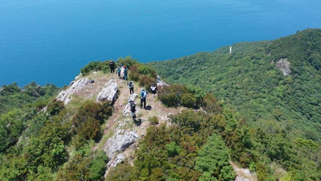 Hikers on a green mountain peak overlooking the ocean