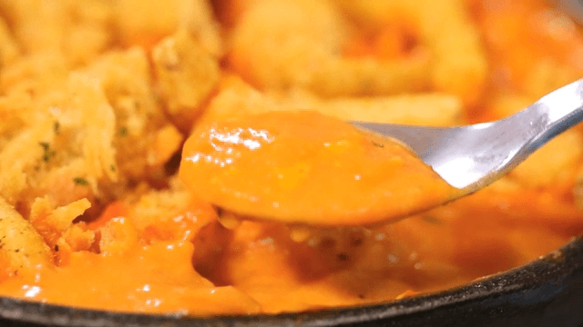 Spoonful of cream sauce mixed with boneless chicken and French fries