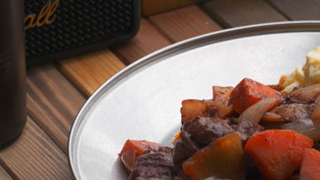 On a wooden table, a plate of roasted meat with vegetables, mashed potatoes, and fresh salad