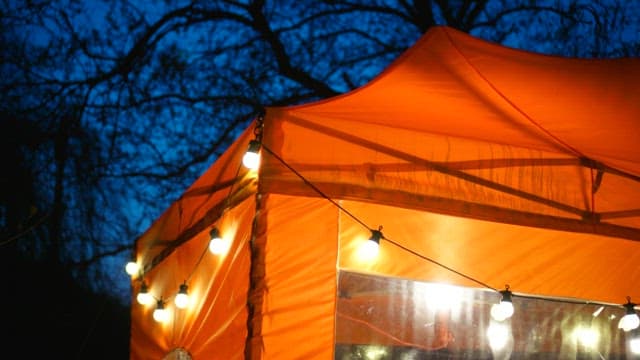 Orange tent awning illuminated by bulb lights at night