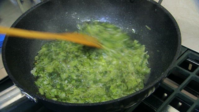 Green onions being stirred in a pan