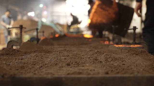 Workers handling molten metal in a factory