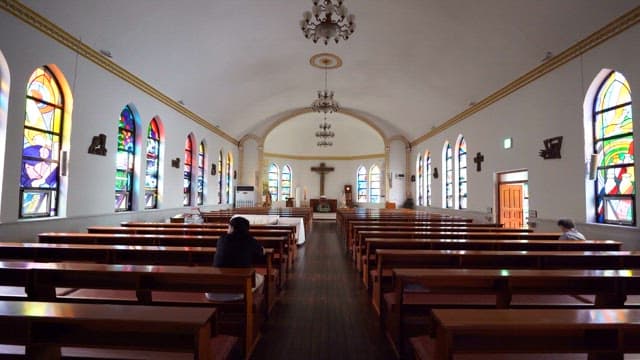 Two people praying in a quiet and empty cathedral