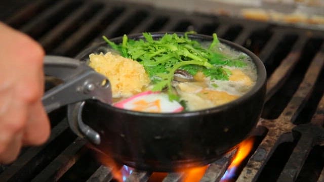 Udon boiling in a pot on a stove with a flame