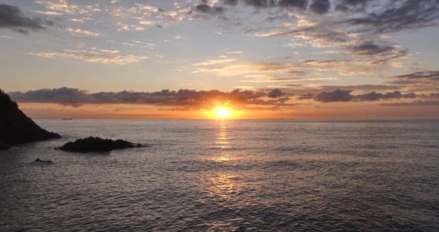 Sunset over the ocean with rocky shore