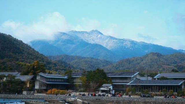 Village of traditional Japanese houses, popular with visitors, beneath a forested mountain